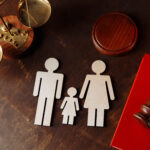 Mother and father figures with child in the. middle next to a judge's gavel.