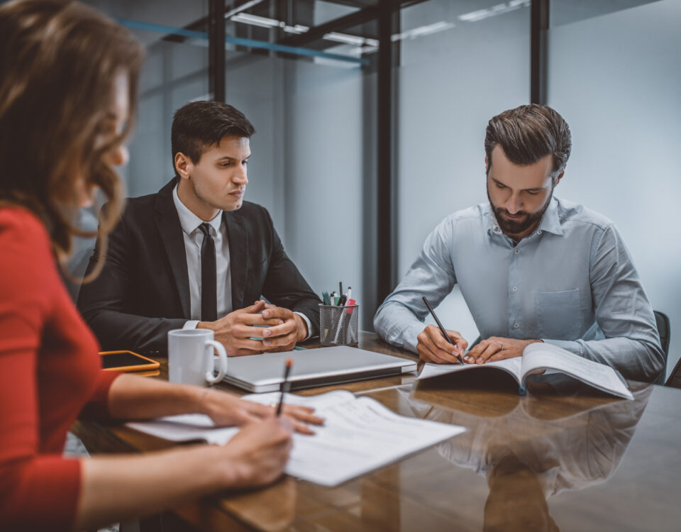 Middle aged couple signing divorce documents at the table with their attorney after divorce mediation.