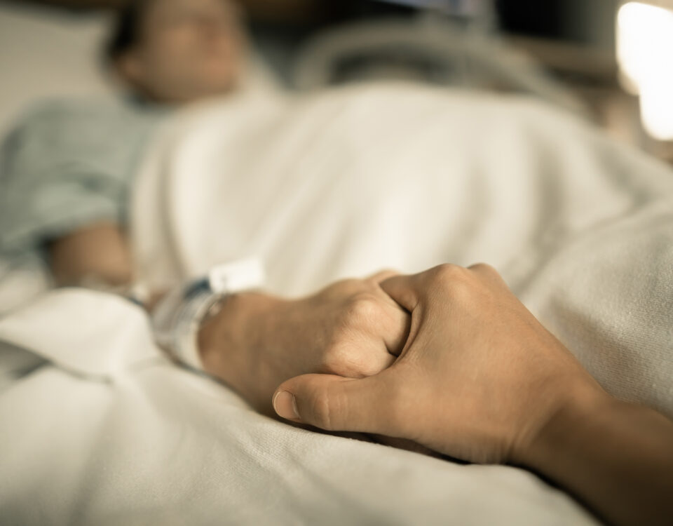 Family member comforting a loved one in a hospital bed suffering due to medical malpractice.