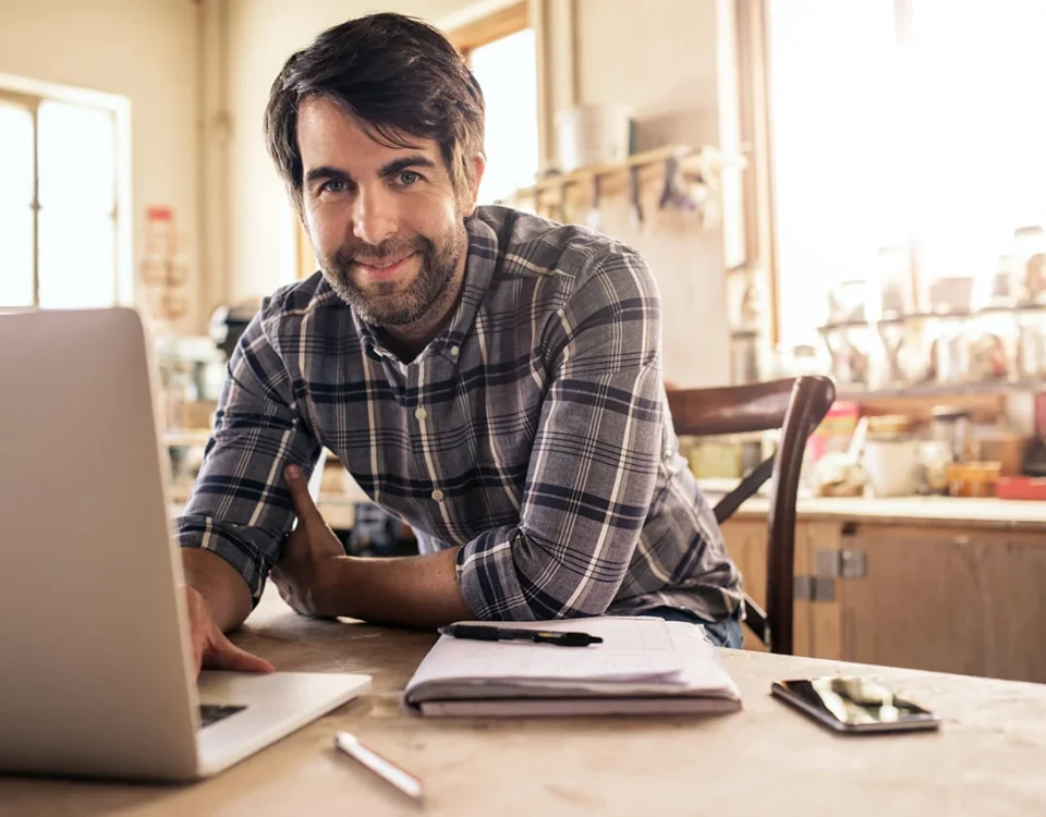 Smiling woodworker using a laptop in his workshop