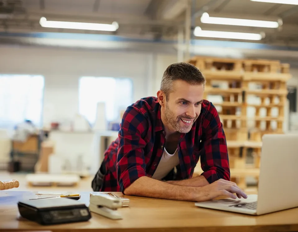 Middle aged Caucasian man working on a laptop in a printing press office